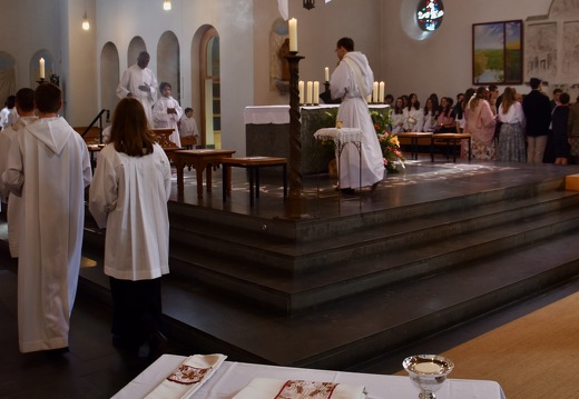 De dos, le futur prêtre, au premier plan le pain et le vin et ses ornements sacerdotaux